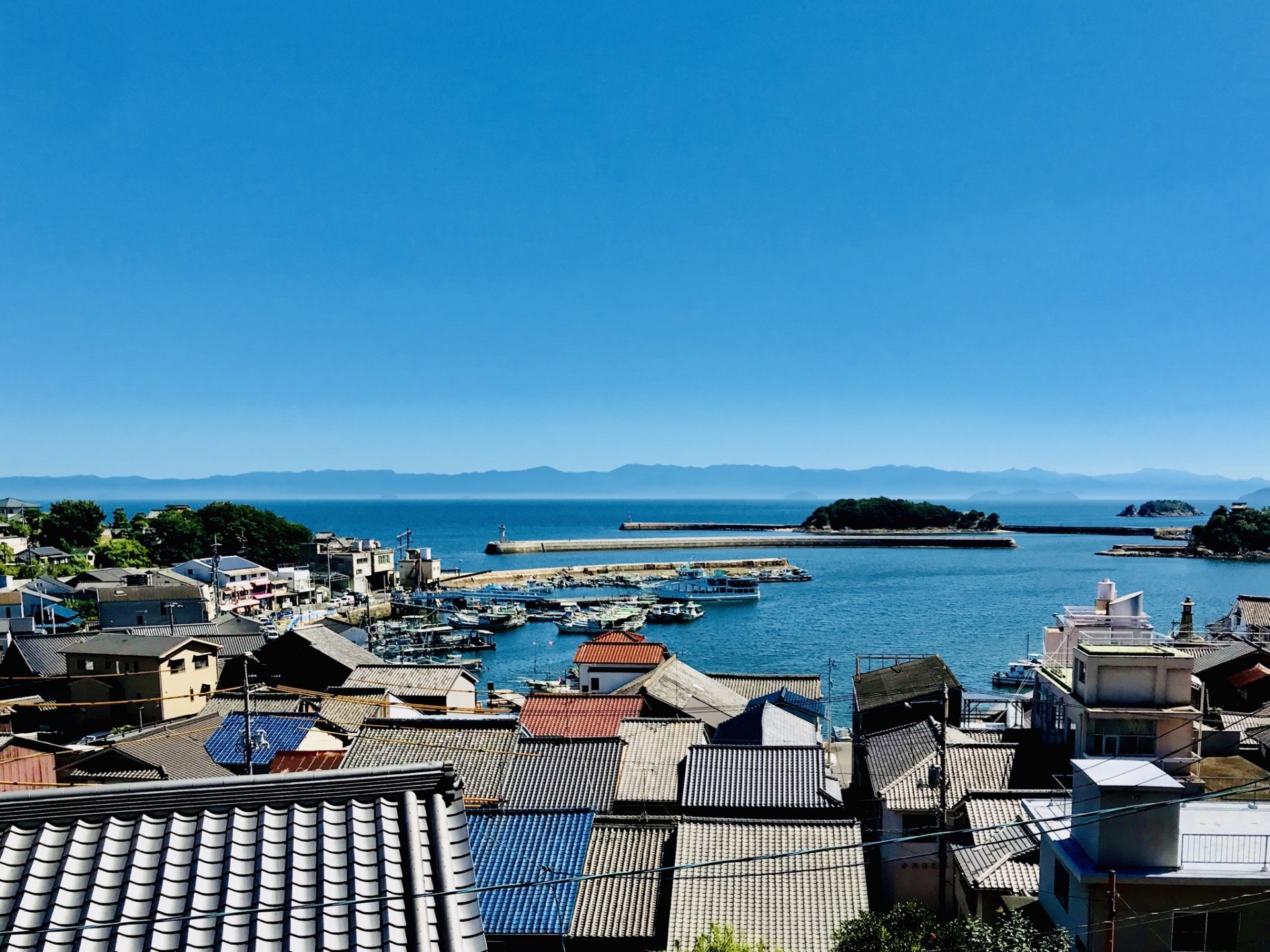 瓦屋根の町並みの向こうに広がる鞆港と瀬戸内海